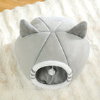 Grey cat-ear cat house from above showing the entrance, soft mat and pom-pom ball